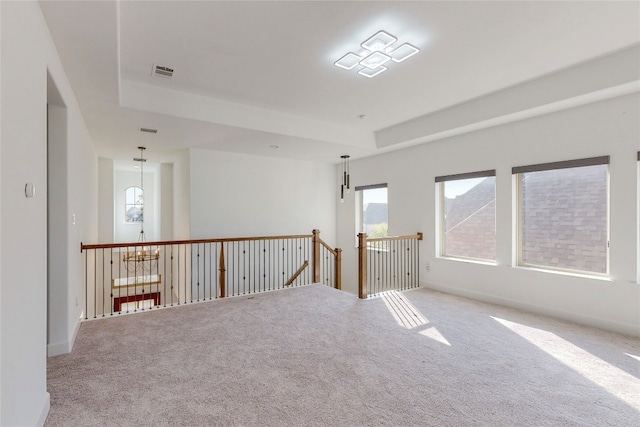 empty room with a tray ceiling and light colored carpet