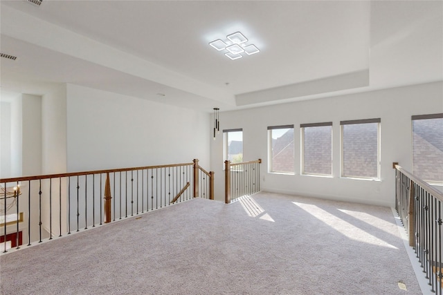 spare room featuring light carpet and a raised ceiling