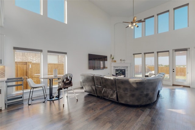 living room featuring ceiling fan, hardwood / wood-style floors, and a towering ceiling