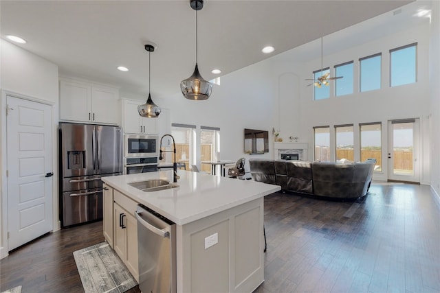 kitchen featuring white cabinetry, dark wood-type flooring, ceiling fan, a kitchen island with sink, and appliances with stainless steel finishes