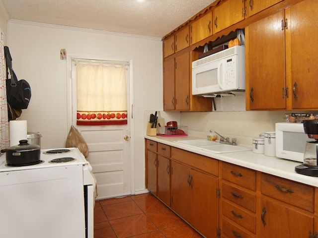 kitchen featuring a textured ceiling, white appliances, dark tile patterned flooring, and sink