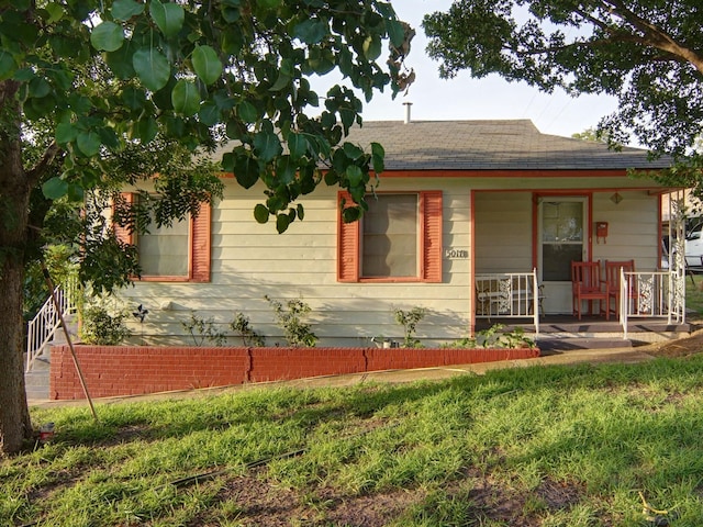 view of side of home featuring a lawn and covered porch