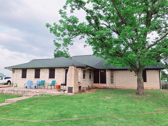 rear view of property with a yard and a storage unit