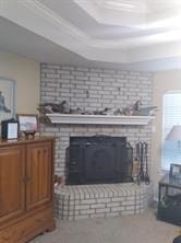 living room featuring brick wall, a raised ceiling, and a fireplace