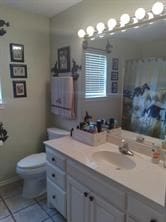 bathroom featuring toilet, tile flooring, and vanity