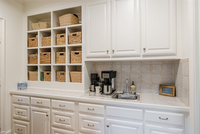 kitchen with tasteful backsplash, white cabinetry, and sink