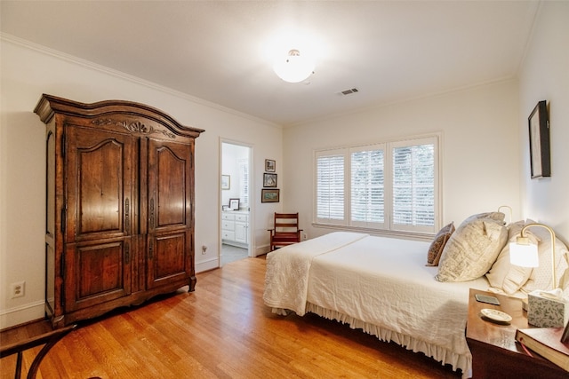 bedroom with ornamental molding, connected bathroom, and light hardwood / wood-style flooring