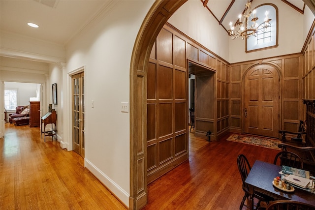 interior space with dark hardwood / wood-style flooring, crown molding, a chandelier, and a high ceiling