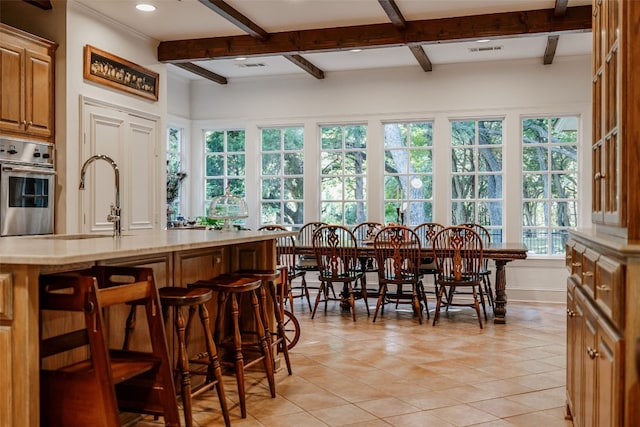 tiled dining room featuring sink and beam ceiling