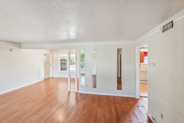 empty room with a textured ceiling and light wood-type flooring