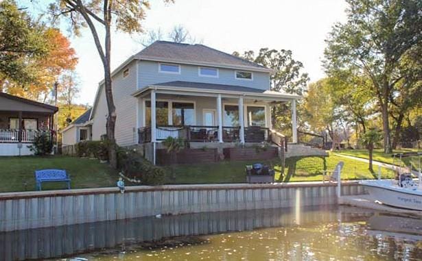 rear view of property with a water view and a lawn