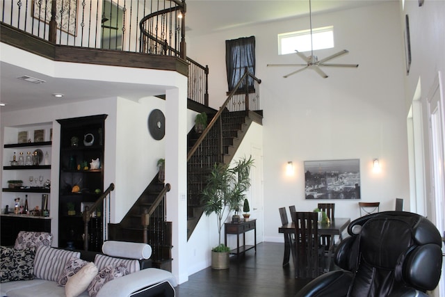 living room featuring dark hardwood / wood-style flooring, built in features, and a high ceiling