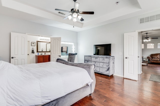 bedroom featuring dark hardwood / wood-style flooring, ceiling fan, and a raised ceiling