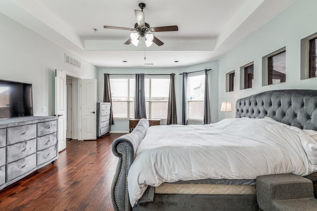 bedroom featuring ceiling fan, dark hardwood / wood-style floors, and a tray ceiling