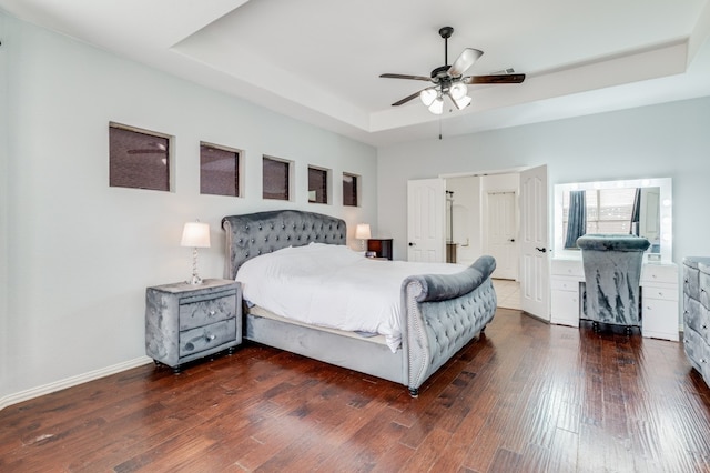 bedroom featuring a tray ceiling, ceiling fan, and dark hardwood / wood-style flooring