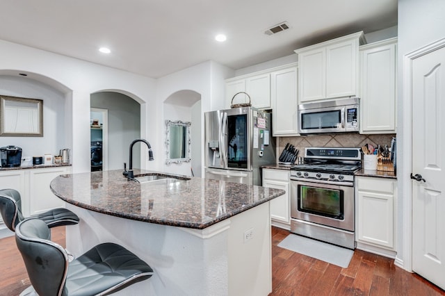 kitchen with dark wood-type flooring, white cabinetry, appliances with stainless steel finishes, backsplash, and sink