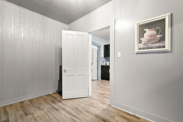 hallway with light wood-type flooring and ornamental molding