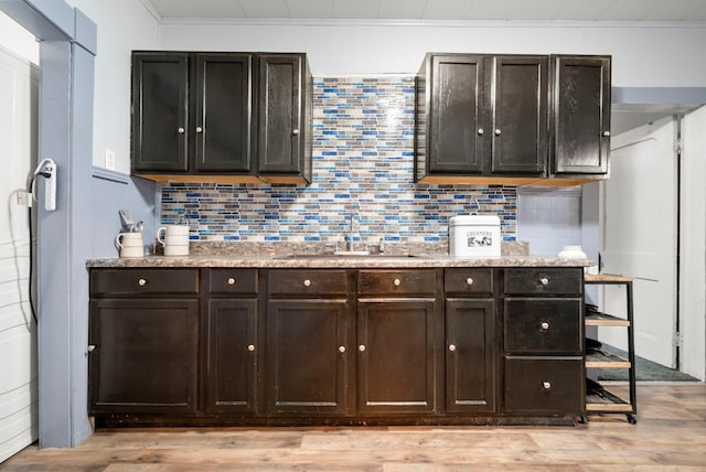 kitchen with backsplash, light hardwood / wood-style flooring, sink, and dark brown cabinetry