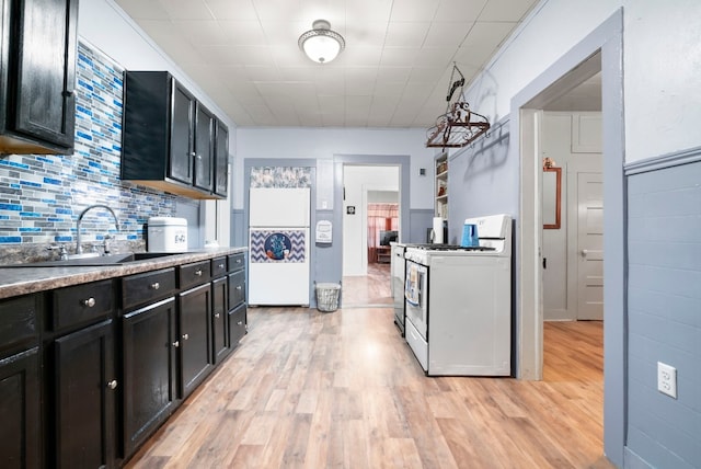 kitchen with tasteful backsplash, light hardwood / wood-style floors, white gas range, and sink