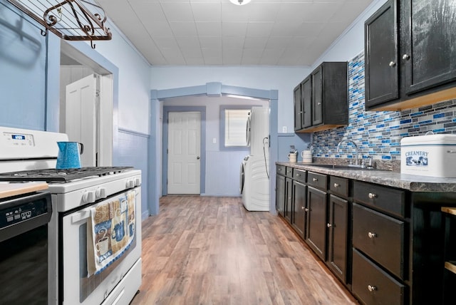 kitchen featuring white gas stove, light wood-type flooring, backsplash, dishwasher, and sink