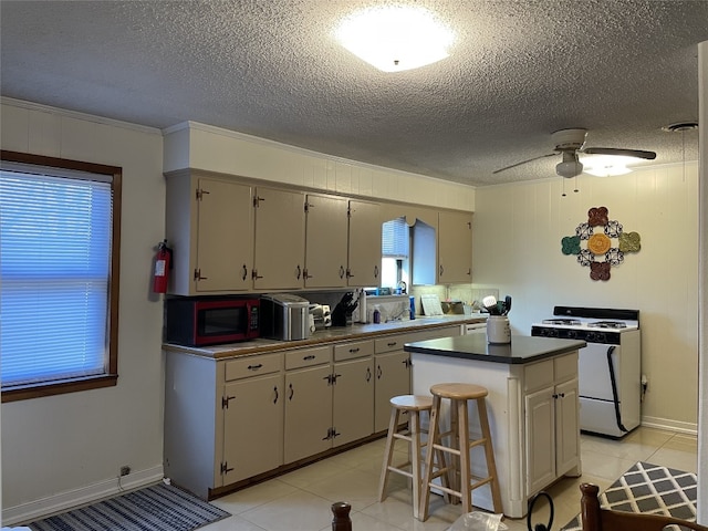 kitchen featuring ceiling fan, a kitchen bar, white range oven, light tile floors, and a kitchen island