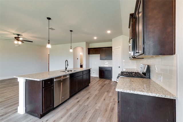 kitchen featuring stove, stainless steel dishwasher, a center island with sink, light wood-type flooring, and sink