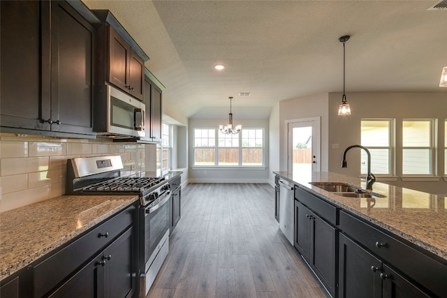 kitchen with stainless steel appliances, decorative light fixtures, wood-type flooring, and an inviting chandelier