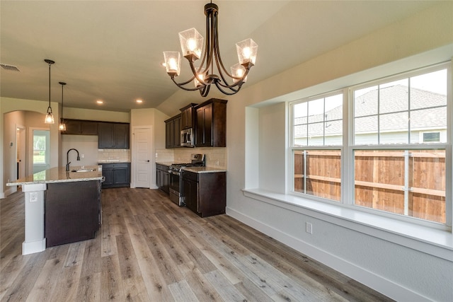 kitchen featuring appliances with stainless steel finishes, backsplash, light wood-type flooring, and pendant lighting