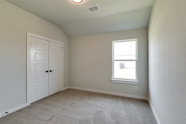 unfurnished bedroom featuring a closet, light colored carpet, and vaulted ceiling