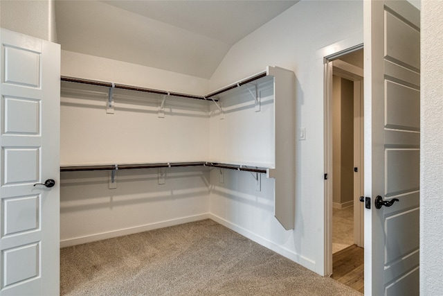 spacious closet with lofted ceiling and light carpet