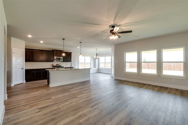 kitchen with decorative light fixtures, light hardwood / wood-style flooring, ceiling fan with notable chandelier, and dark brown cabinetry