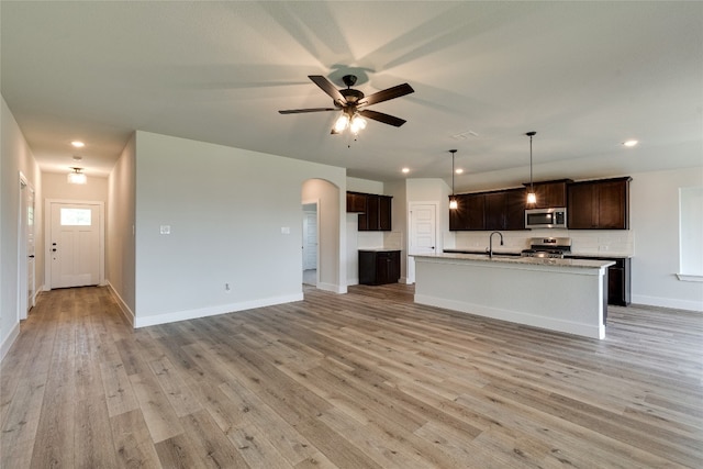 kitchen with a kitchen island with sink, ceiling fan, light hardwood / wood-style flooring, and decorative light fixtures