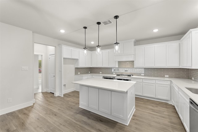 kitchen featuring hanging light fixtures, white cabinetry, light wood-type flooring, a kitchen island, and tasteful backsplash