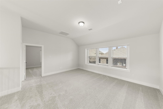 empty room with light colored carpet and vaulted ceiling