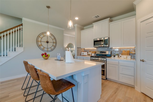 kitchen featuring light hardwood / wood-style floors, tasteful backsplash, white cabinets, a kitchen bar, and stainless steel appliances