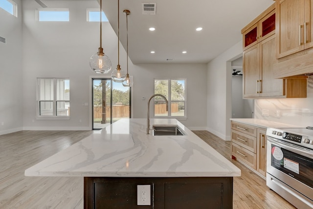 kitchen with electric range and an island with sink