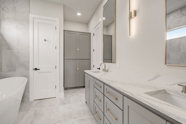 bathroom featuring double vanity, tile patterned flooring, a bath, and tile walls