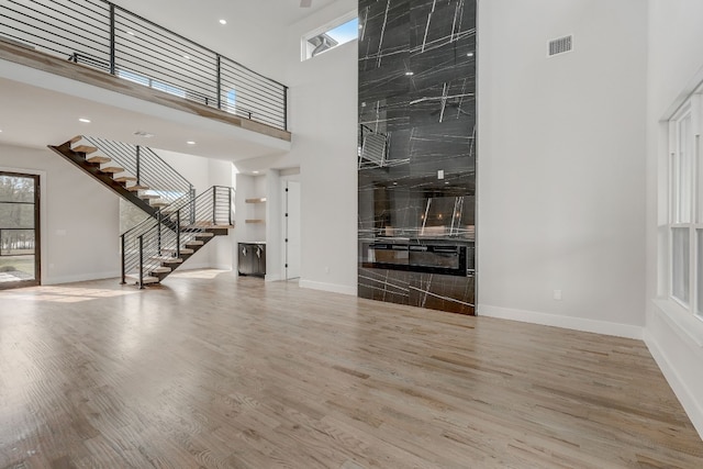 unfurnished living room with a fireplace, wood-type flooring, and a towering ceiling