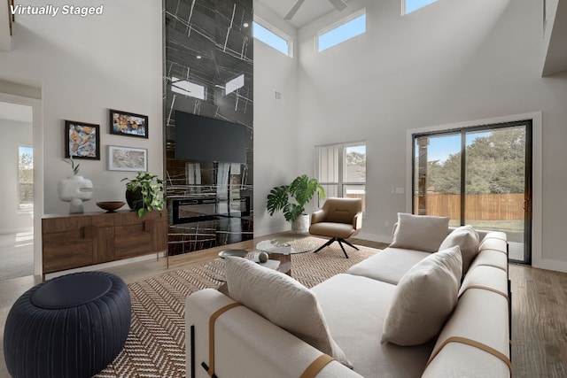 living room with a tile fireplace, hardwood / wood-style floors, and a towering ceiling