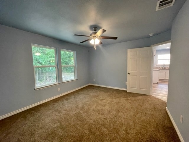 carpeted spare room featuring ceiling fan