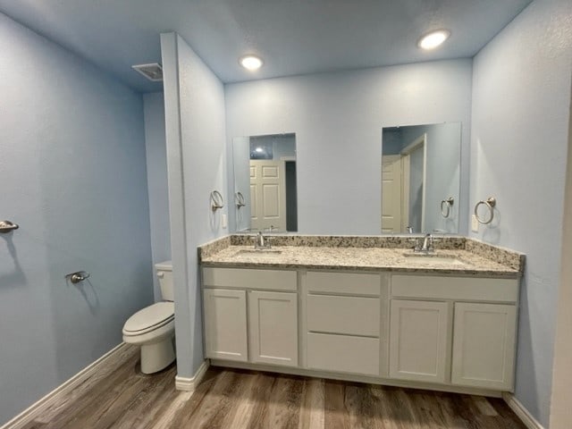 bathroom featuring dual vanity, toilet, and hardwood / wood-style flooring