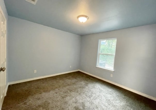 unfurnished room featuring dark colored carpet