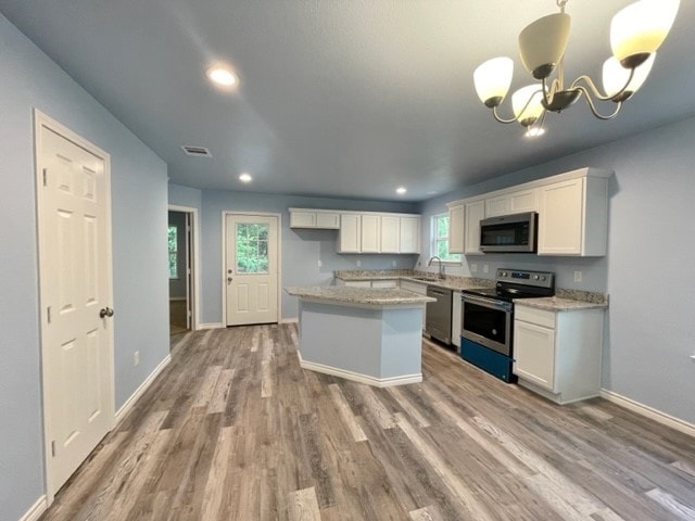 kitchen with a chandelier, pendant lighting, stainless steel appliances, and white cabinetry