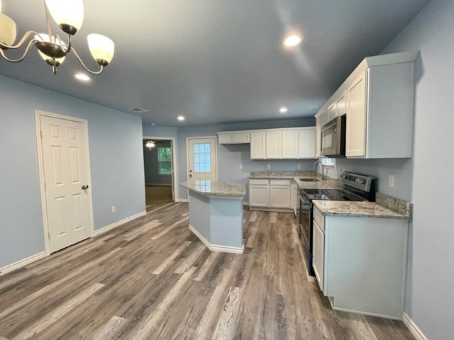 kitchen featuring white cabinets, stainless steel range with electric stovetop, a chandelier, a kitchen island, and hardwood / wood-style flooring