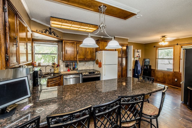 kitchen featuring a kitchen breakfast bar, plenty of natural light, decorative light fixtures, appliances with stainless steel finishes, and ornamental molding