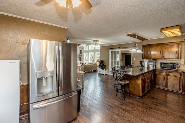 kitchen with pendant lighting, french doors, stainless steel fridge, kitchen peninsula, and a breakfast bar area