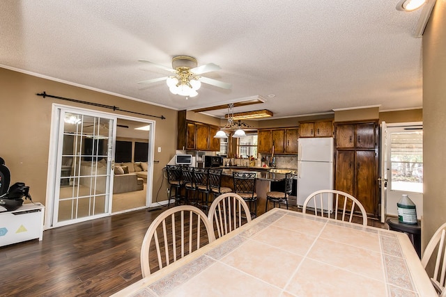 dining room with hardwood / wood-style flooring, ceiling fan, crown molding, and a textured ceiling