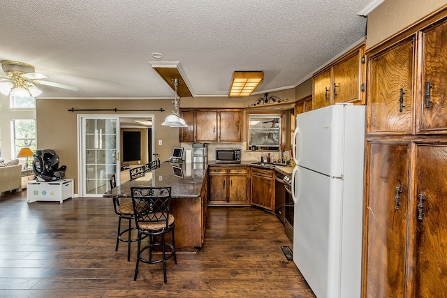 kitchen featuring a kitchen breakfast bar, a textured ceiling, ceiling fan, dark wood-type flooring, and white refrigerator