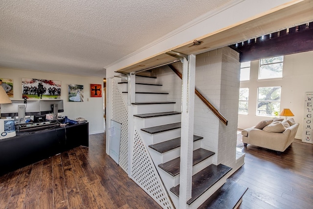 staircase with hardwood / wood-style floors, a textured ceiling, and crown molding