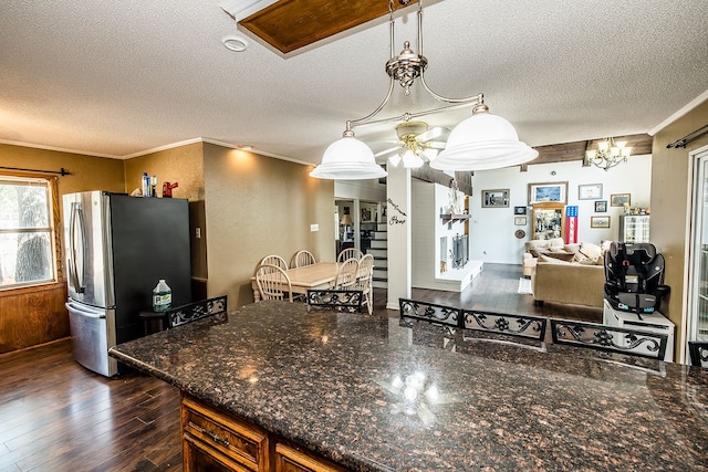 kitchen featuring stainless steel fridge, dark hardwood / wood-style flooring, a textured ceiling, crown molding, and pendant lighting